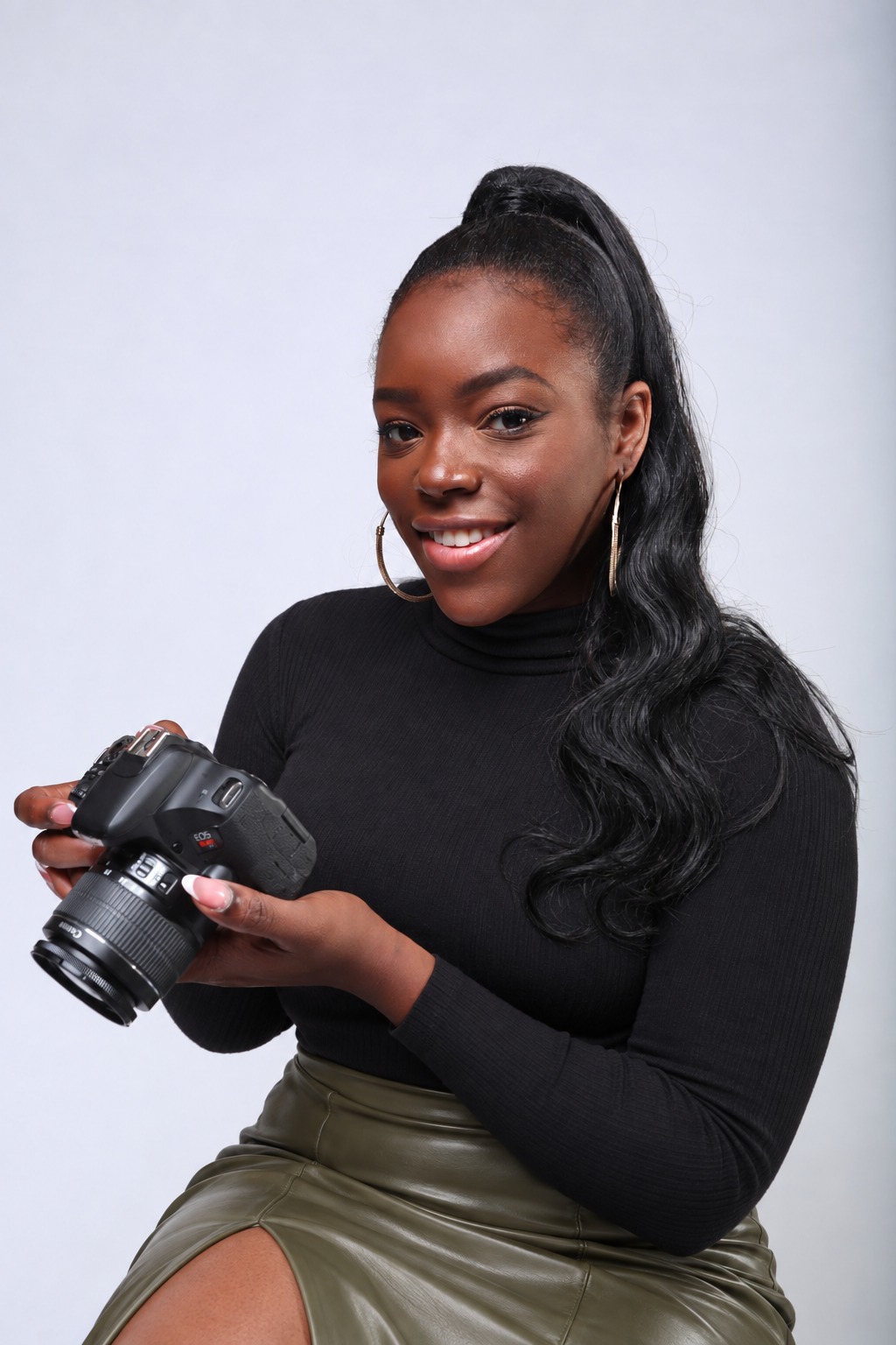 Bri, founder of MissBriMichelle Media, smiling and holding her camera